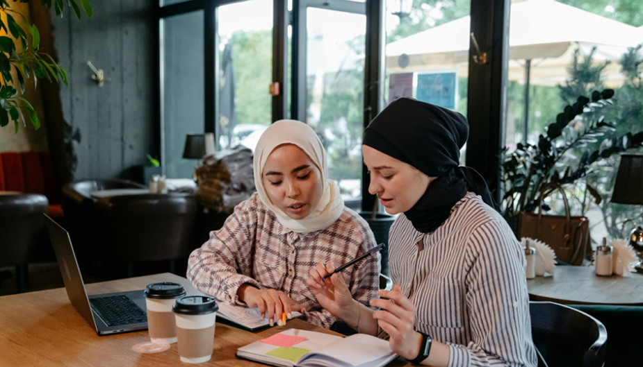 two Muslim sit at a coffee shop while working together