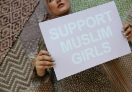 Muslim woman holding up a sign saying Support Muslim Girls