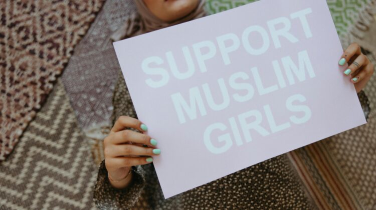 Muslim woman holding up a sign saying Support Muslim Girls
