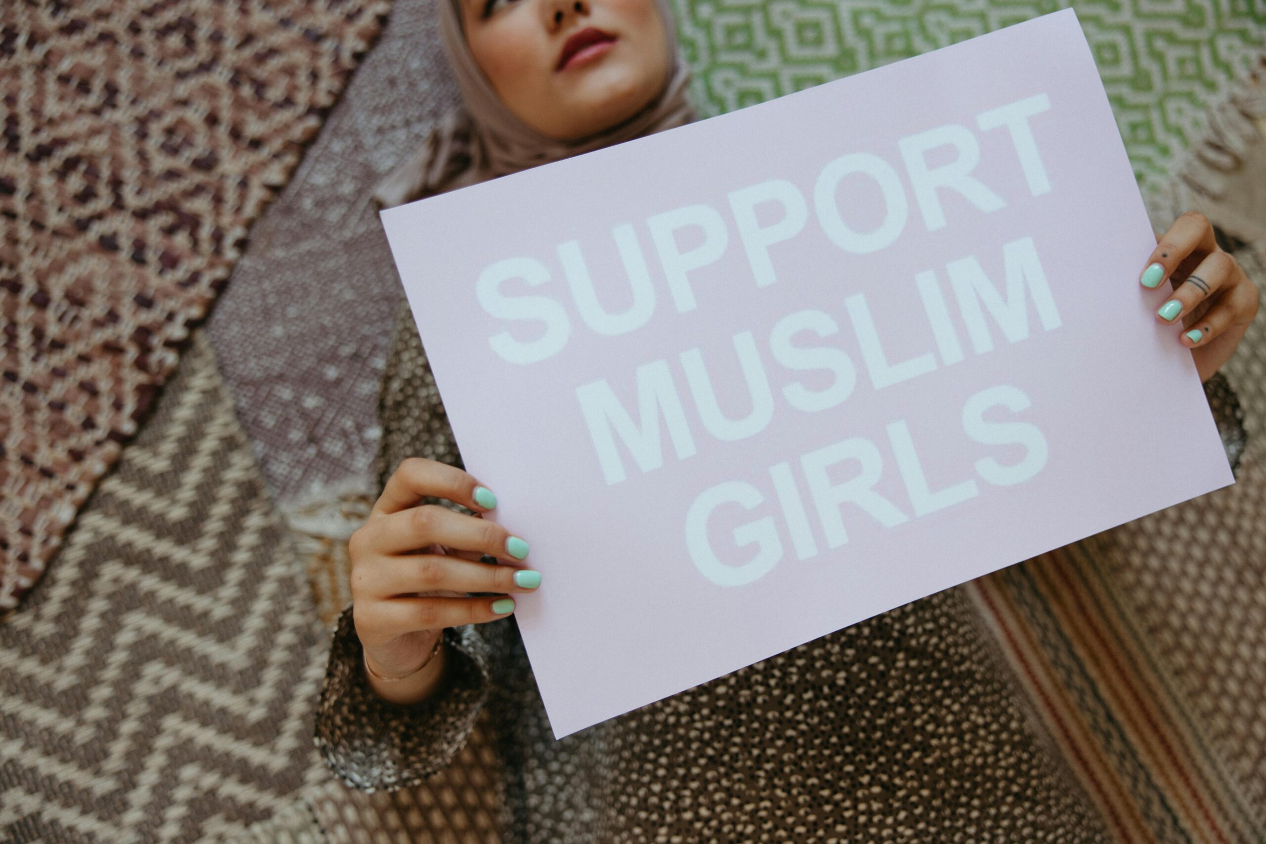 Muslim woman holding up a sign saying Support Muslim Girls