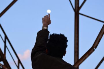 a man reaches up to the sky steel beams surround him