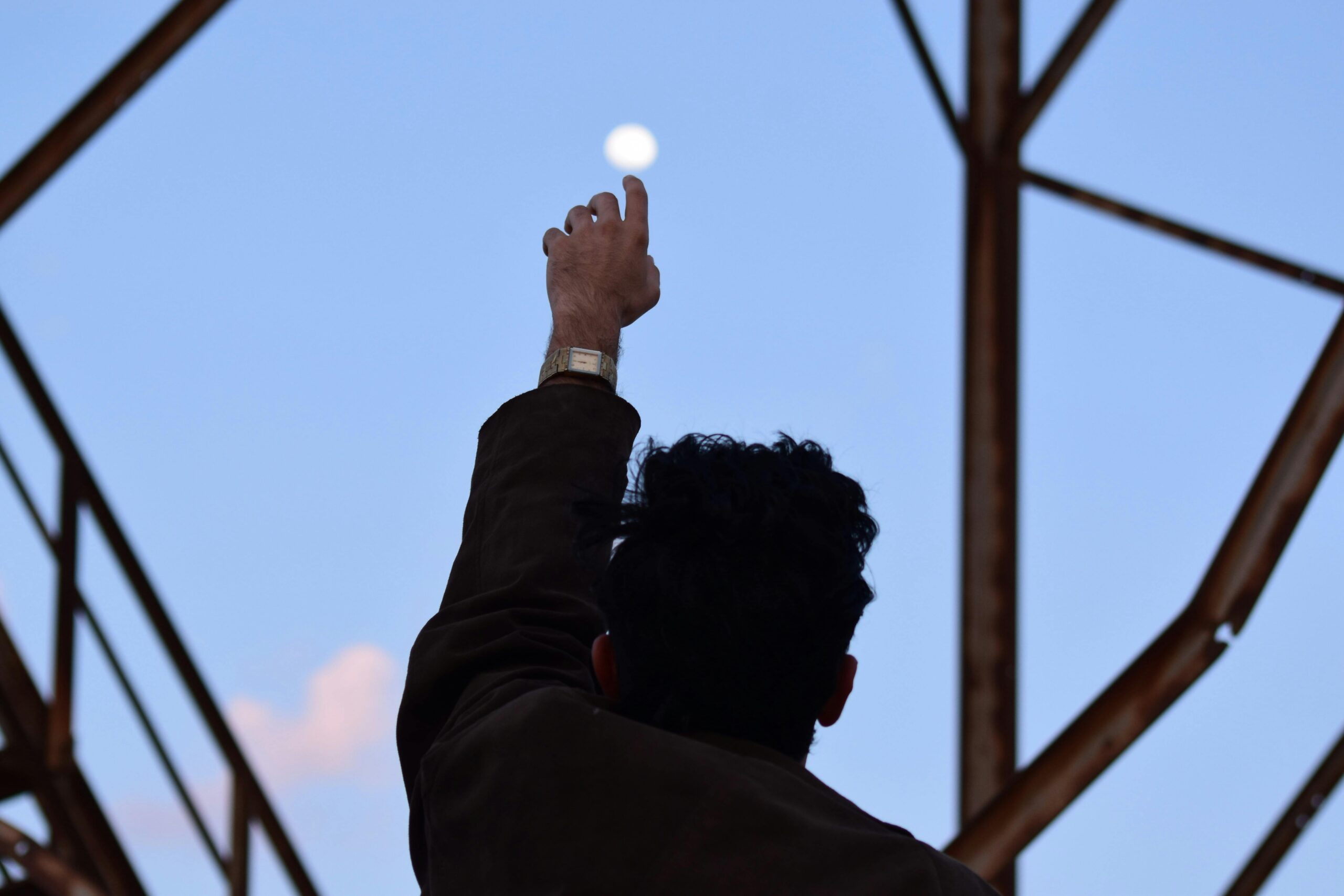 a man reaches up to the sky steel beams surround him